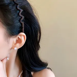 Close-up detail of a vintage matte wavy tortoiseshell headband on model's dark hair