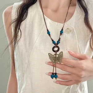Vintage bohemian butterfly pendant necklace with blue ceramic beads on a model.