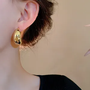 Vista dettagliata di un orecchino a goccia d'oro a forma di C indossato da una modella