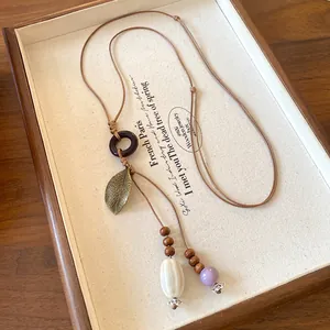 Handmade ethnic bohemian necklace featuring a ceramic oval pendant and antique leaf charm