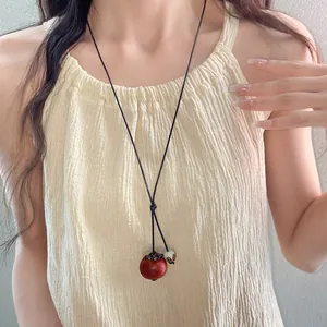 Close-up of ethnic ceramic necklace with red persimmon pendant on a female model