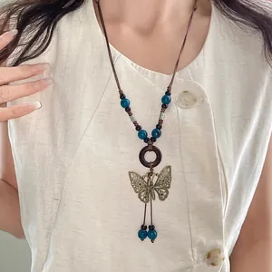 Detailed view of bohemian bronze butterfly pendant necklace with blue ceramic beads