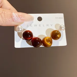 Detailed view of round resin pearl earrings with 925 silver needle on a display card