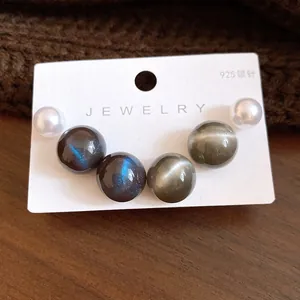 Macro view of six round resin pearl stud earrings on a white jewelry display card