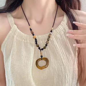 Detailed close-up of a bohemian ethnic ceramic oval necklace on a female model.
