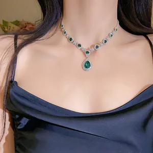 Vista dettagliata di una collana vintage con ciondolo a goccia verde smeraldo su modella
