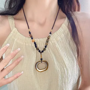 Close-up detail of ethnic bohemian ceramic oval pendant necklace worn by a female model