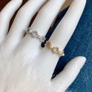 Anello con quadrifoglio placcato oro 18k con perle e zirconi su mano di modella in stile elegante
