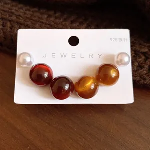 Close-up of minimalist round resin and pearl stud earrings on a white jewelry card.