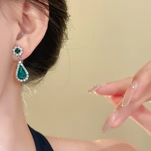 Dettaglio ravvicinato di un lussuoso orecchino a goccia verde smeraldo vintage con diamanti