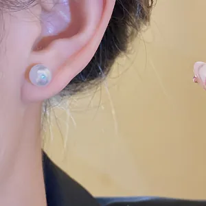Close-up of minimalist round resin pearl stud earring with iridescent finish.
