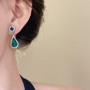 Dettaglio di orecchini vintage di lusso con gocce color smeraldo e pavé di diamanti
