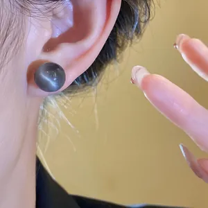 Close-up of a minimalist round grey resin pearl stud earring elegantly worn on an ear