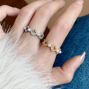 Primo piano dettagliato di eleganti anelli floreali con pavé di zirconi e perle bianche