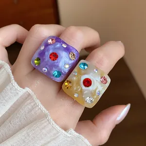 Closeup view of two colorful chunky resin rings with sparkling multicolored rhinestones