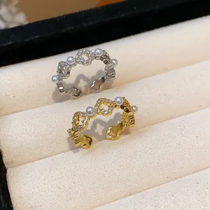 Dettaglio ravvicinato di eleganti anelli a fiore placcati oro 18k con perle e zirconi