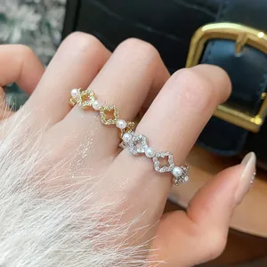 Dettaglio ravvicinato di anelli a fiore placcati in oro 18k con zirconi e perle