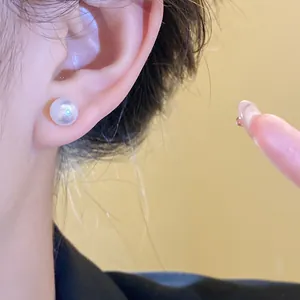 Macro view showing a lustrous round resin pearl stud earring worn on a model's ear