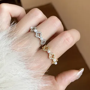 Dettaglio ravvicinato di anelli placcati in oro 18 carati con zirconi e piccole perle.