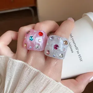 Close-up detail of dopamine-style chunky marbled resin rings with colorful rhinestones