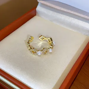 Dettaglio ravvicinato di un delicato anello a fiore placcato oro 18k con perle e zirconi