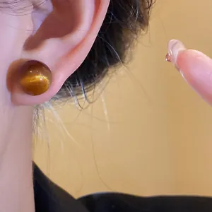 Detailed macro view of a round amber resin cat-eye earring showing shimmering texture