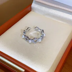 Primo piano di un anello placcato oro 18 carati con fiori di zircone e perle in una scatola.