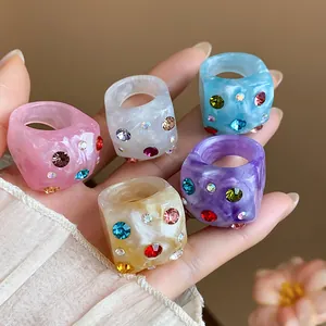 Detailed view of colorful chunky resin rings with sparkling multi-colored rhinestones.