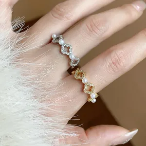 Dettaglio di anelli a quadrifoglio placcati oro e argento con perle e zirconi
