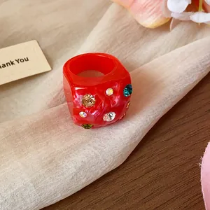 Close-up of a red dopamine-style wrinkled ring with colorful inlaid rhinestones.