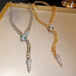 Elegant gold and silver rhinestone snake necklaces with green eyes on a display tray.