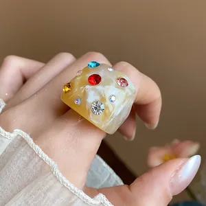 Detailed close-up showing a chunky marble textured resin ring with colorful rhinestones
