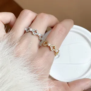 Primo piano di eleganti anelli a fiore placcati in oro 18k con zirconi e piccole perle