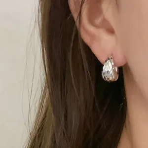 Elegant silver-toned pleated U-shaped hoop earrings worn by a model for a chic look