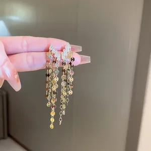 Detail of golden sequin tassel earrings with sparkling crystals on a silver needle base