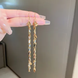 Detailed view of long gold leaf sequin tassel drop earrings with silver needle
