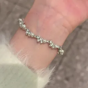 Close-up of elegant irregular pearl and zircon bracelet on wrist with white sleeve