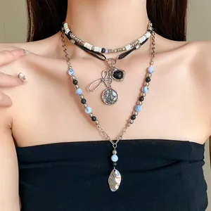 Multi-layered vintage necklace with ethnic beads and silver-toned leaf pendant worn by model