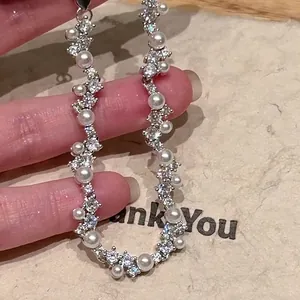 Close-up detail of an elegant irregular zircon and pearl bracelet being held by a hand