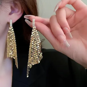 Detail view of elegant gold sequin mesh tassel earrings with sparkling rhinestone studs.