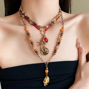 Close-up detail of ethnic layered beaded necklace with red gemstone and gold coin pendants