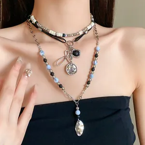 Close-up of ethnic multi-layer beaded necklace with vintage bow and coin pendants