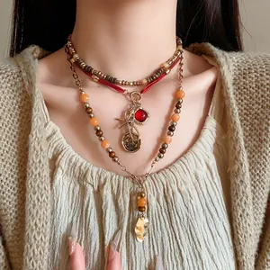 Close-up of ethnic beaded multi-layer necklace with vintage leaf and coin pendants