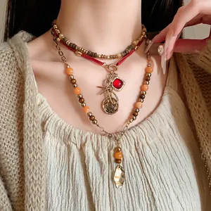 Detailed close-up of layered ethnic beaded necklaces featuring gold coins and red gem