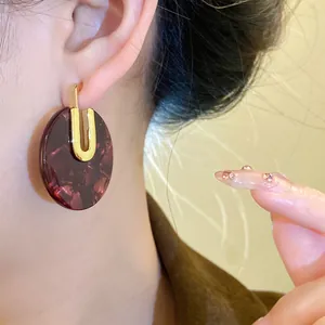 Primo piano di orecchini rotondi in acetato tartarugato con dettaglio in oro 18K.