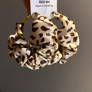 Detail of leopard print fabric-wrapped hoop earrings with elegant scrunchie texture.