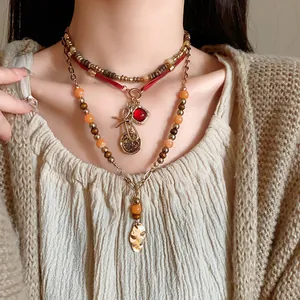 Detail view of layered ethnic beaded necklace with red gemstone and metal bow pendants