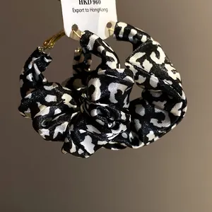 Close-up detail of retro fabric-wrapped leopard print hoop earrings with hanging tag