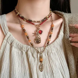 Close-up of ethnic style multi-layer beaded necklace with bow and red stone charms