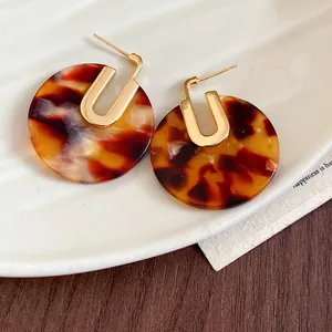 Primo piano di orecchini tondi in acetato tartarugato con perni placcati in oro 18 carati